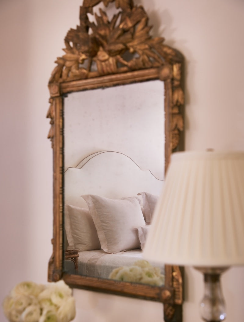 Detail shot of mirror in bedroom reflecting bed