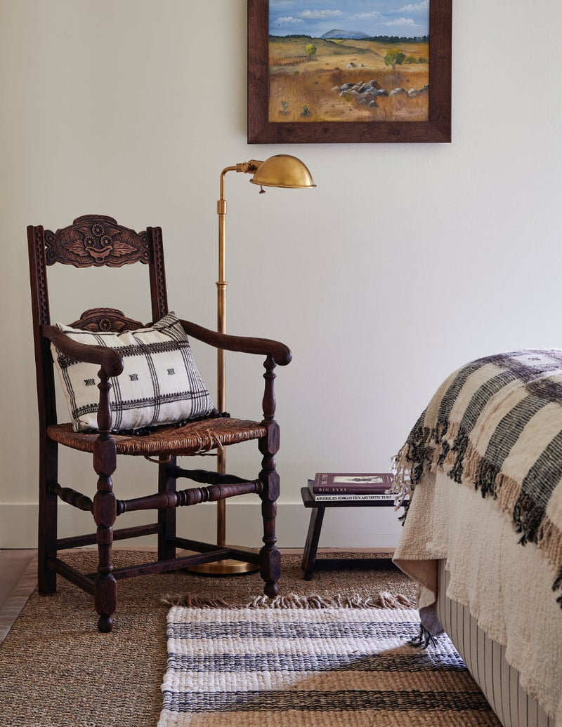 Dark wood side chair with floor lamp at bedside