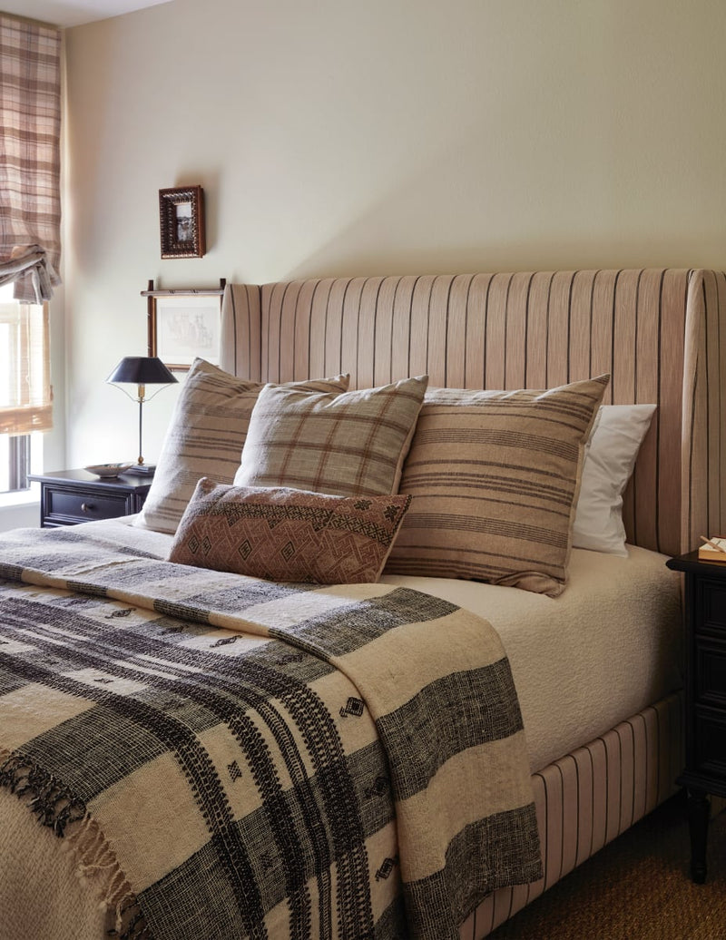 Bed with folded striped throw and striped linen pillows