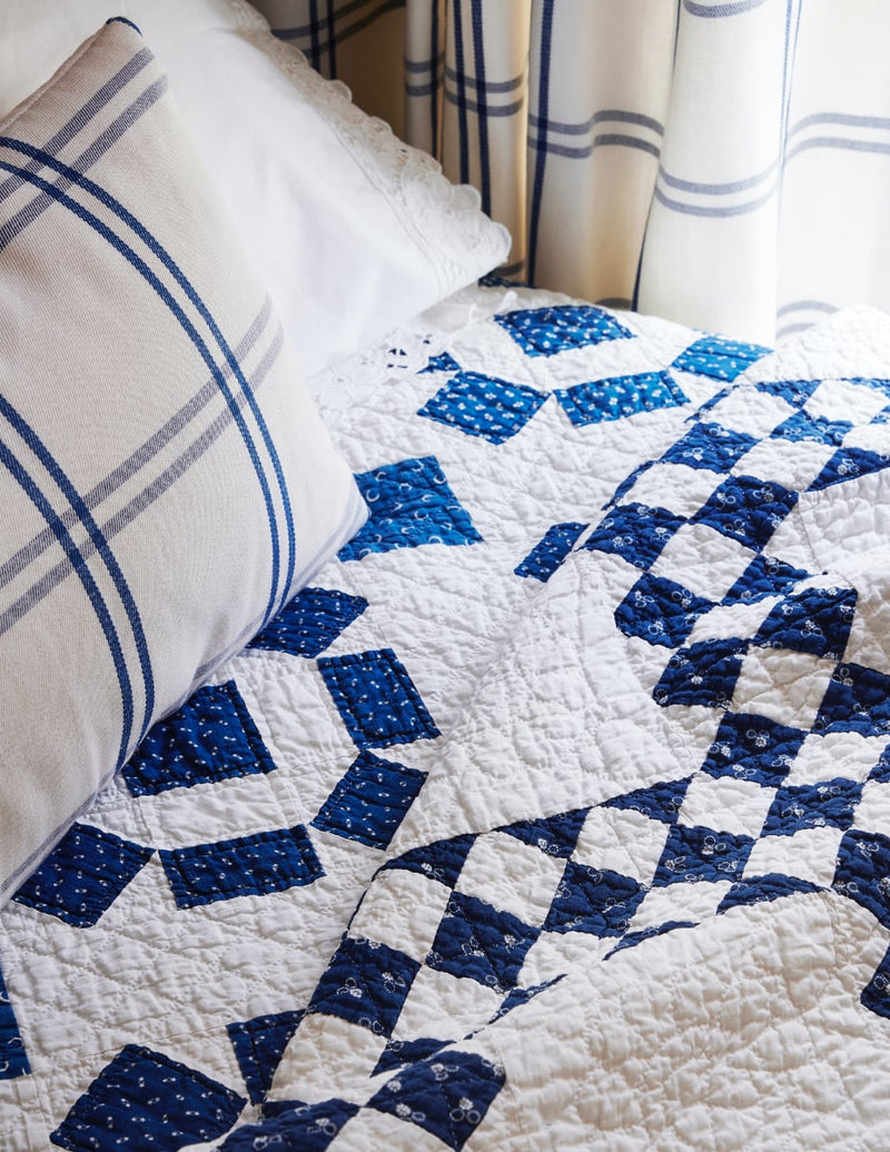 Closeup of blue and white coverlet on bed