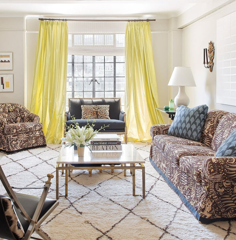 Printed sofa in front of window with yellow drapery