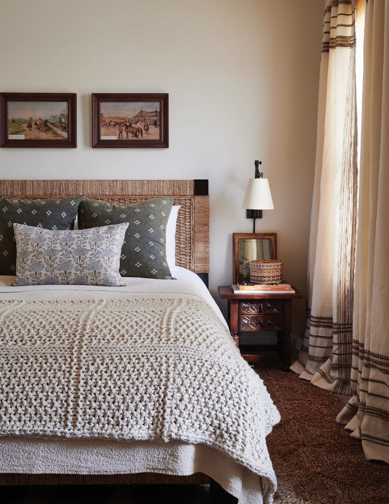 Bed with knitted throw and printed linen pillows